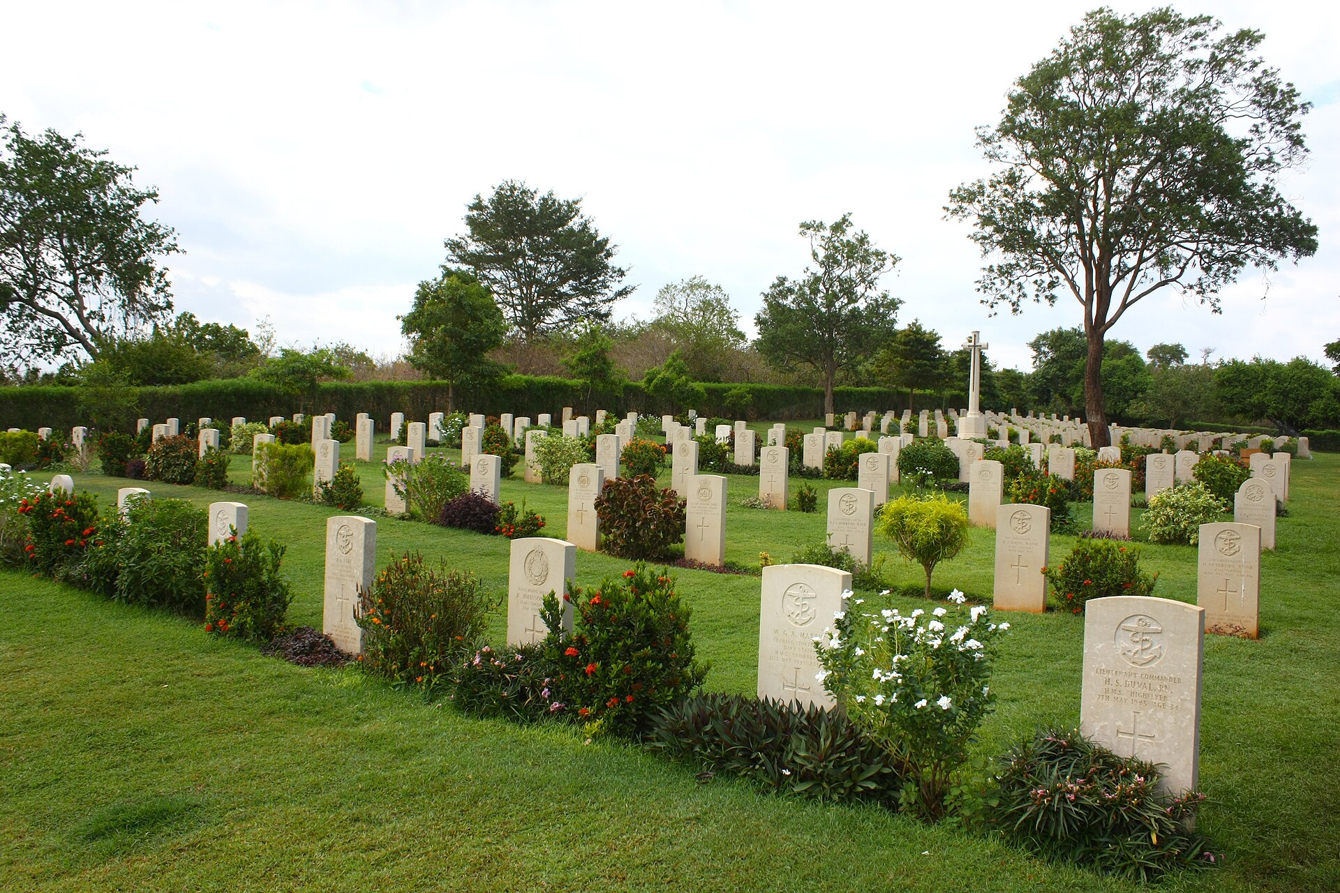 Rows of white headstones among flowering shrubs at Trincomalee War Cemetery