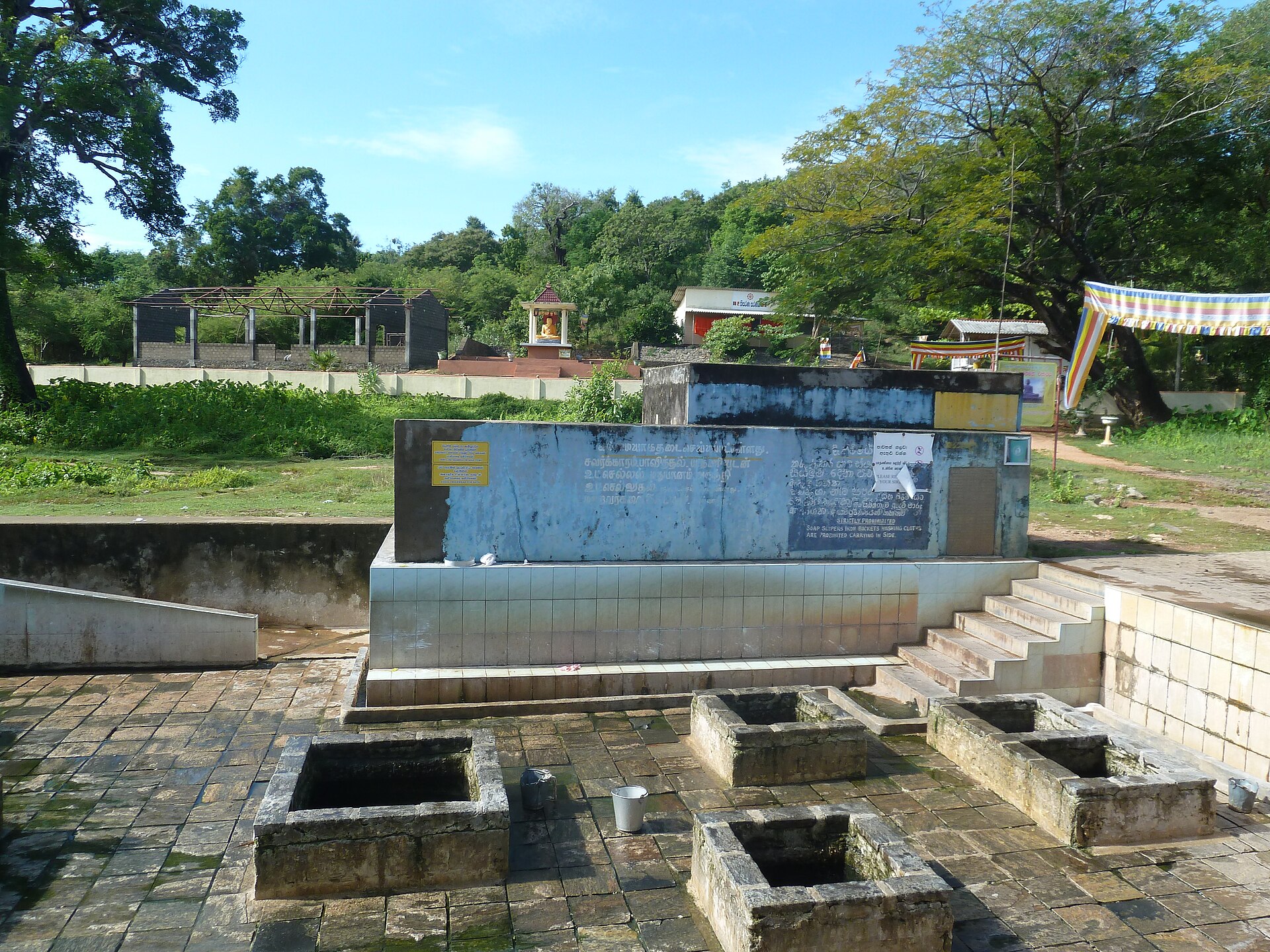 Stone-rimmed hot water wells with buckets, and a small shrine behind